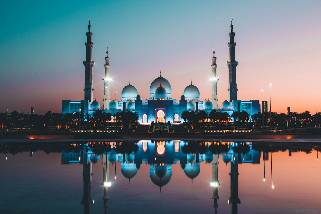 The Sheikh Zayed Grand Mosque reflected in a pool at low sun in Abu Dhabi
