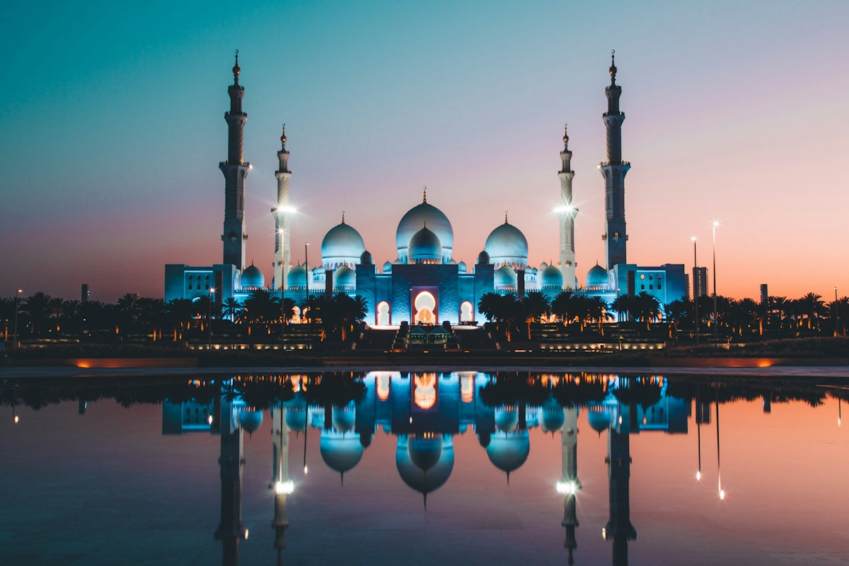 The Sheikh Zayed Grand Mosque reflected in a pool at low sun in Abu Dhabi