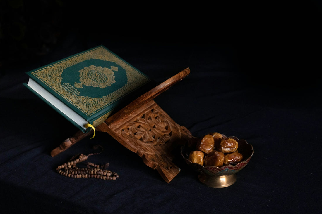 A green Quran on a wooden stand beside dates and prayer beads